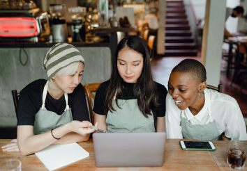 Staff in a cafe sitting around a laptop